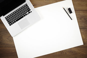 Laptop, Bleistift und Radiergummi auf großem Blatt Papier