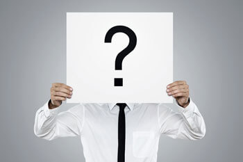 Mann im Hemd hält weißes Schild mit einem Fragezeichen vor seinem Gesicht